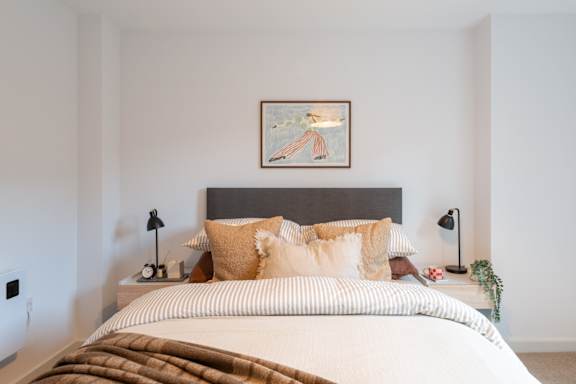 A bed with a brown blanket and tan pillows is in the image.