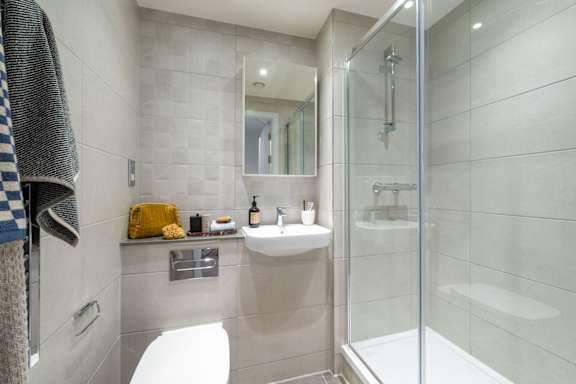 A bathroom with a white toilet, sink, and shower.