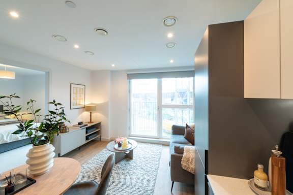 A modern living room with a large window and a grey rug.