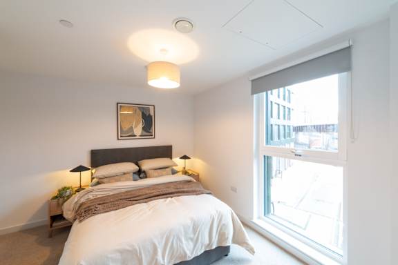 A bedroom with a large bed and a window overlooking a cityscape.