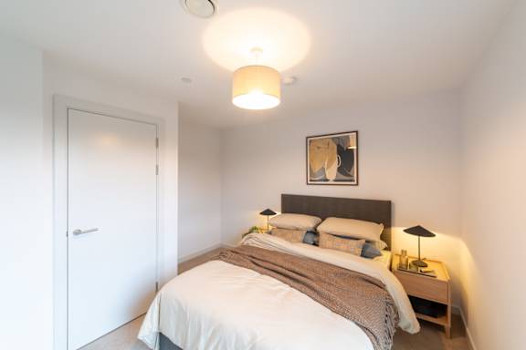 A bedroom with a bed, nightstand, and lamp.