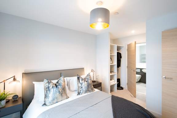 A bedroom with a large bed and a lamp on the side table.