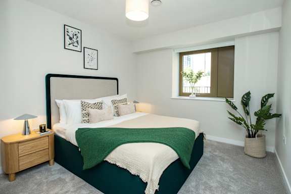 A bedroom with a large bed and a green blanket.