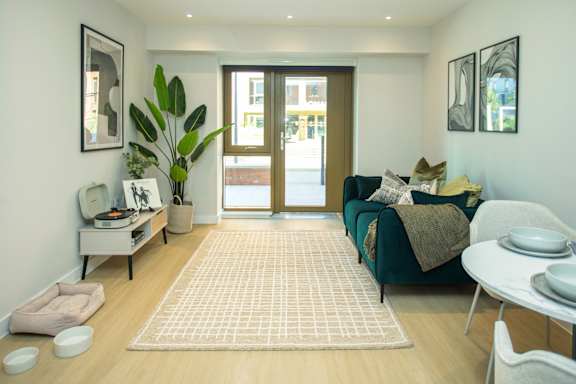 A living room with a green couch and a white table.