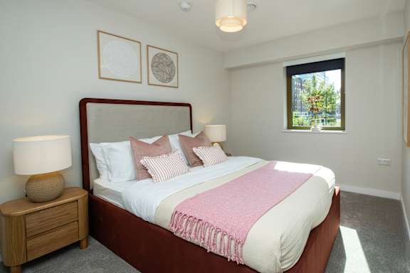 A bedroom with a large bed and a window showing a tree outside.