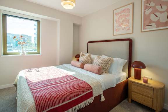A bedroom with a bed, nightstand, and window.
