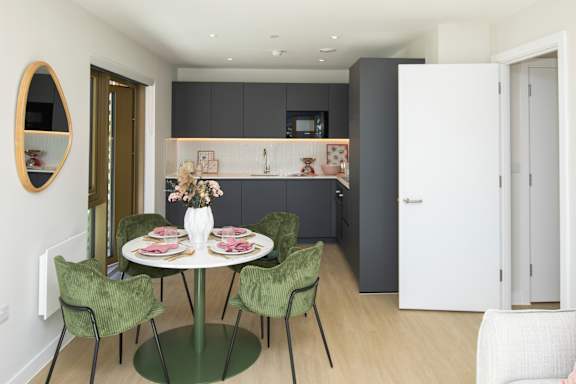 A dining room with a white table and green chairs.