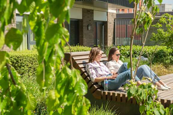 Lush green garden with two women sitting on the bench at The Lark, London, SW11 7EA