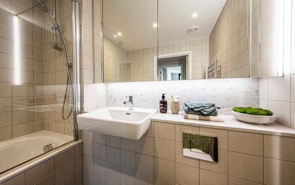 A bathroom with a sink, mirror, and shower.