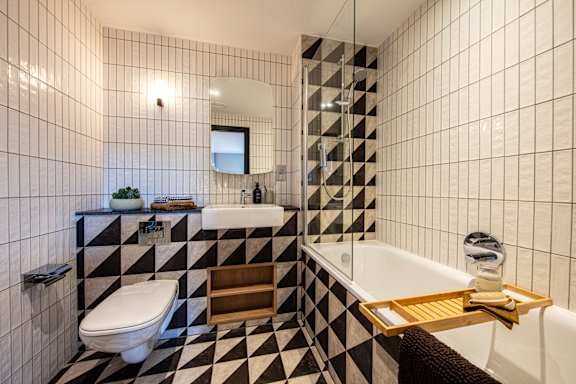 A black and white tiled bathroom with a white toilet, sink, and bathtub.