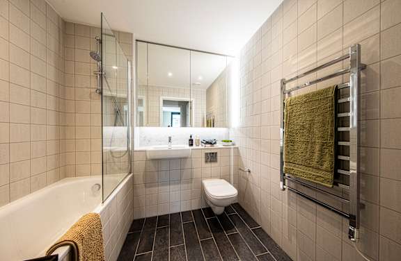 A modern bathroom with a white bathtub, toilet, and a glass shower door.