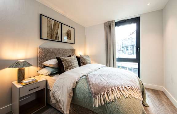 A bedroom with a large bed and a nightstand with a lamp.