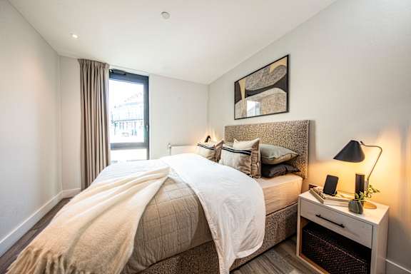 A bedroom with a bed, nightstand, and window.
