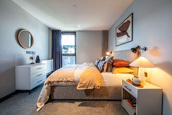 A bedroom with a bed, nightstand, and a window with curtains.