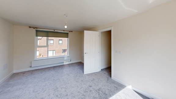 A room with a window and a door is empty and waiting to be furnished.