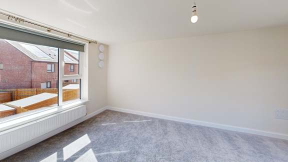 A room with a window showing a view of a red brick building outside.