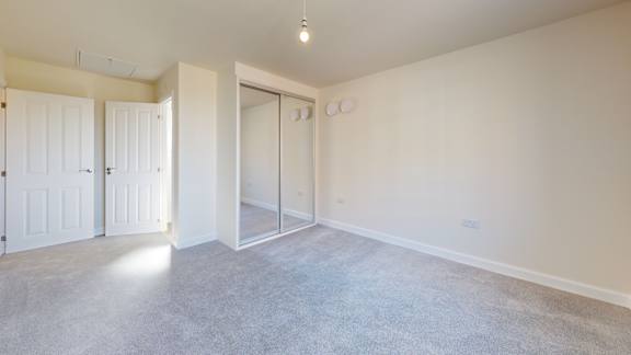 A room with white walls and a grey floor with a door on the left and a sliding door on the right.