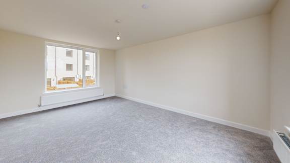 A large empty room with a window overlooking a building.