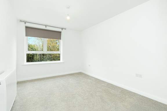 A white room with a window and a radiator on the wall.