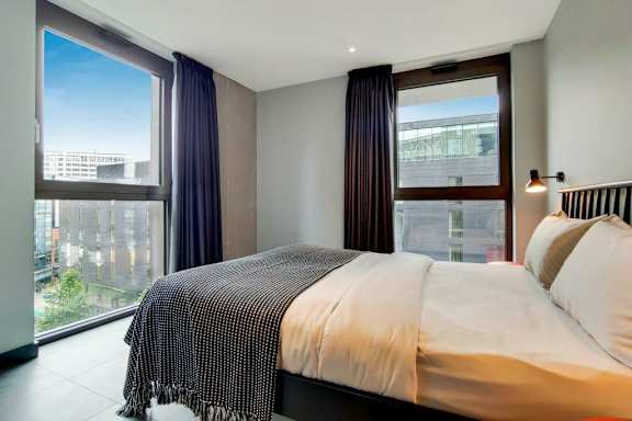 A bedroom with a large bed and a view of the city at Beton Apartments, Wembley, HA9 0SL