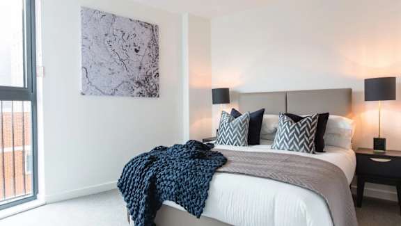 a bedroom with a bed and a large window a bedroom with a bed and a large window at Vox Apartments, Manchester, M15 4YD