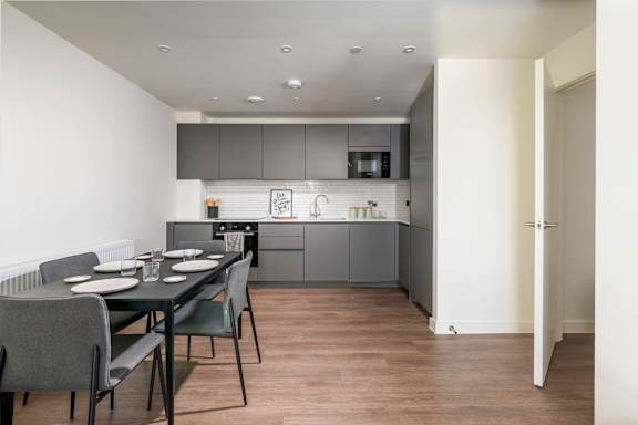 A modern kitchen with a dining table set for two.