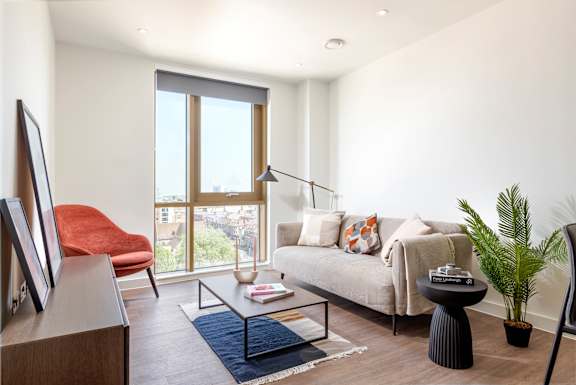 A living room with a couch, chair, and a table with a plant on it.