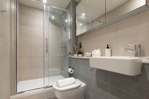 A white toilet sits next to a walk-in shower with a glass door.