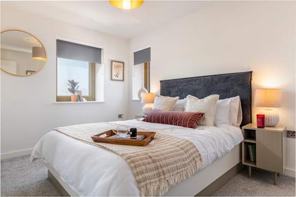 A bedroom with a large bed and a tray with a cup and saucer on it.