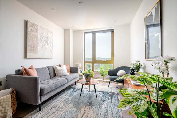 A living room with a grey couch, a coffee table, and a large window.