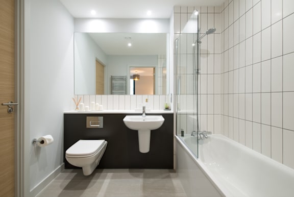 A white sink is on a black countertop in a bathroom.