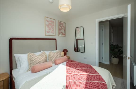 A bedroom with a bed, pillows, and a mirror.