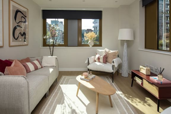 A living room with a white couch, a coffee table, and a large window.