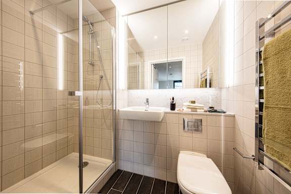 A white toilet is in a modern bathroom with a walk-in shower.