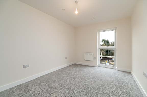 A room with a window and a carpeted floor.