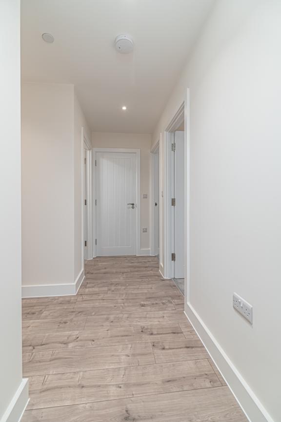 A long hallway with a white door at the end.