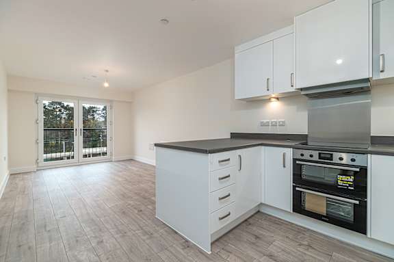 A kitchen with white cabinets and a black countertop.