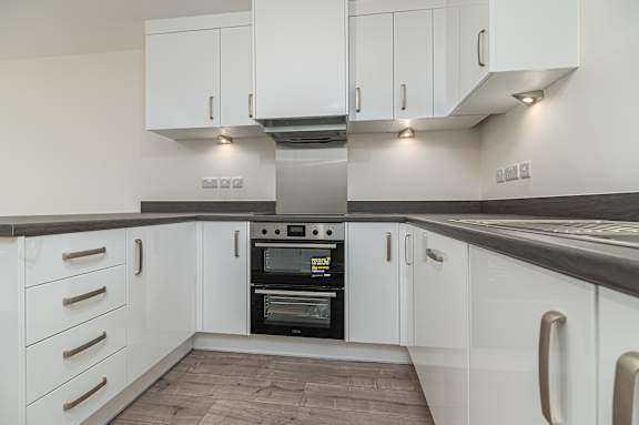 A modern kitchen with white cabinets and a stainless steel oven.