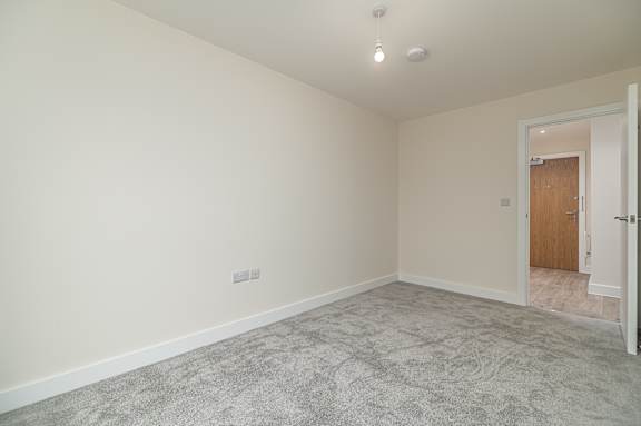 A room with a carpeted floor and a door on the right side.