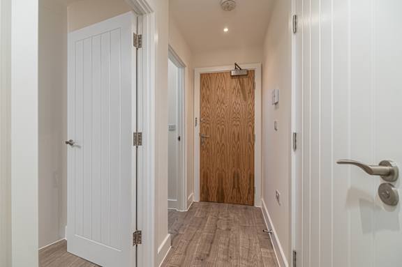 A hallway with a white door on the left and a wooden door on the right.