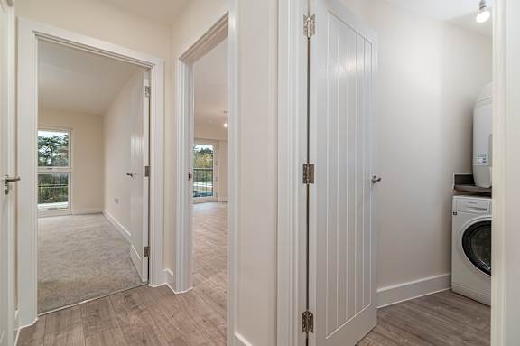 A white door is open to a room with a washing machine.