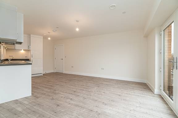 A spacious room with wooden flooring and white walls.
