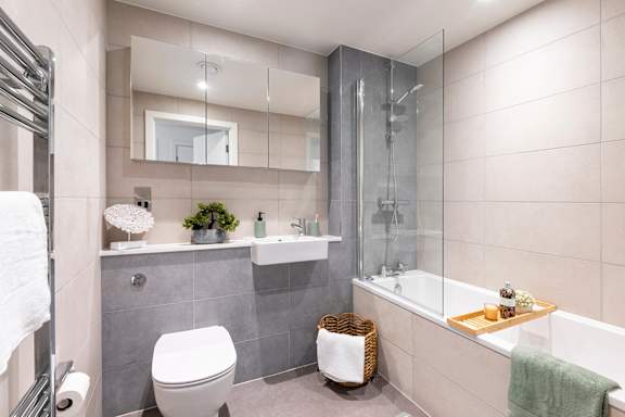 A bathroom with a white toilet, a sink, and a glass shower stall.