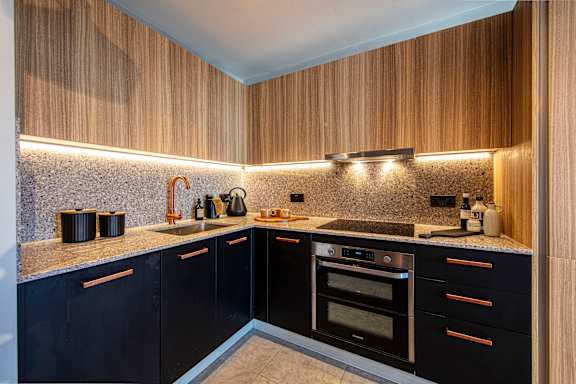 A modern kitchen with dark cabinets and wooden accents.
