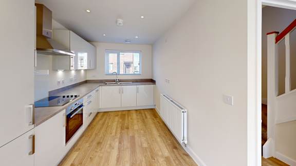 A kitchen with white cabinets and a wooden floor.