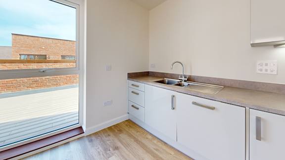 A kitchen with white cabinets and a window overlooking a brick building.