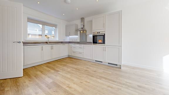 A kitchen with white cabinets and a wooden floor.