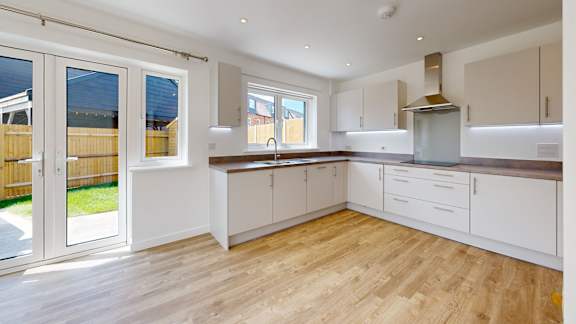 A kitchen with white cabinets and a wooden floor.