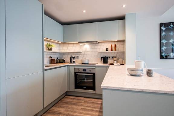 A modern kitchen with a marble countertop and stainless steel appliances.