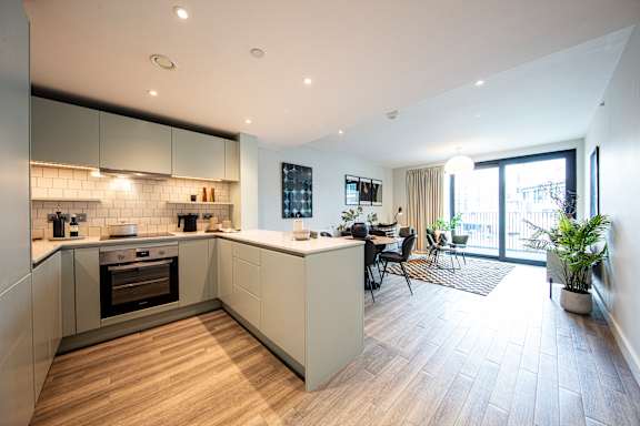 A modern kitchen with a wooden floor and white walls.